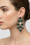 Close-up of a woman wearing a pair of green teardrop earrings with a white background